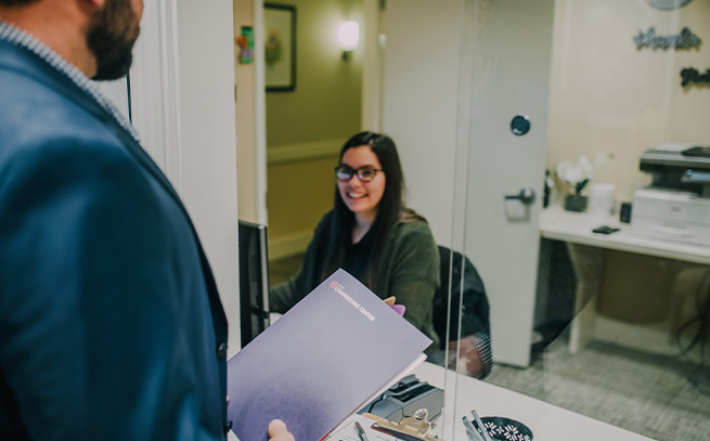 front desk receptionist and patient holding a folder