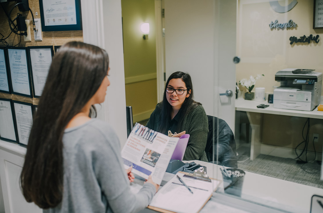 A patient getting information at the front desk