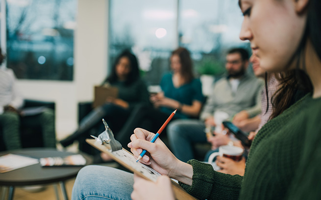 a patient in a group therapy session writing on a clipboard